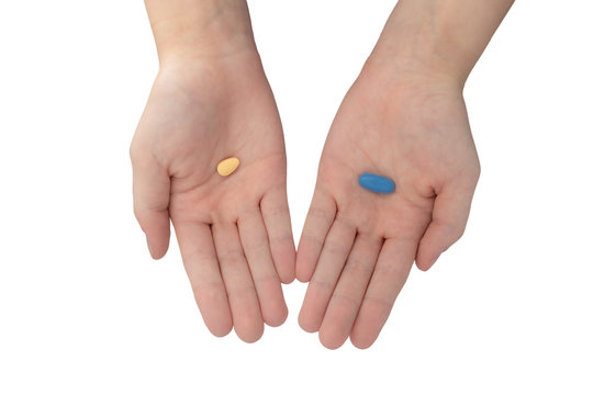 Young woman's hands offering blue and brown pills isolated on white background