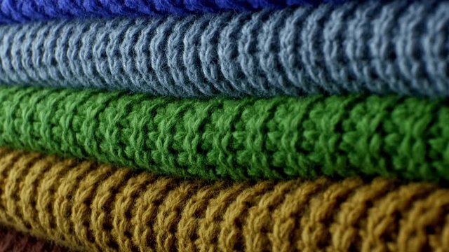 Neatly folded winter multi-colored clothes. Tilt shot