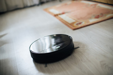 robotic vacuum cleaner on laminate wood floor smart cleaning technology. modern household wireless device for cleaning house. smart home concept