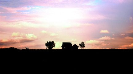 La silueta de una casa en medio de la nada con un relajante atardecer en el fondo.