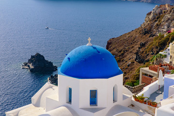 Fototapeta na wymiar Blue domed church and traditional white houses facing Aegean Sea in Oia, Santorini, Greece