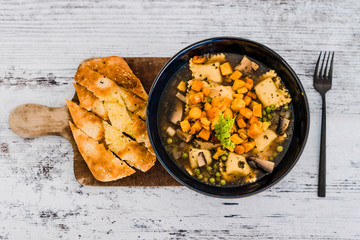 vegan ravioli with vegetable broth peas and pumpkin and side of garlic bread