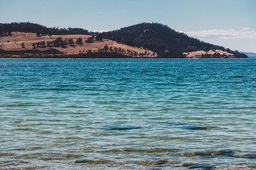 wild Tasmanian landscape and pristine turquoise water of the Derwent River as seen from Legacy Beach