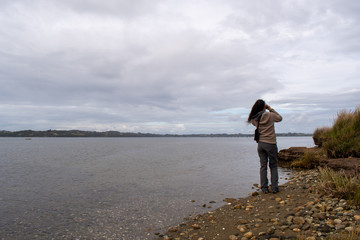 A joung woman looking birds through binoculars in a wetland