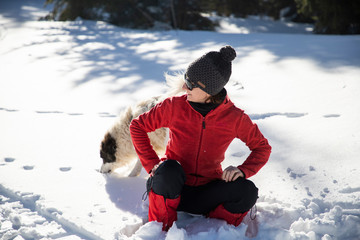 Naklejka premium happy woman and dog playing in fresh snow
