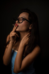 Portrait of Asian/Japanese/Korean/Indian brunette young girl in blue bath towel  and spectacles smoking cigarette in black studio copy space background. Indian lifestyle and fashion photography