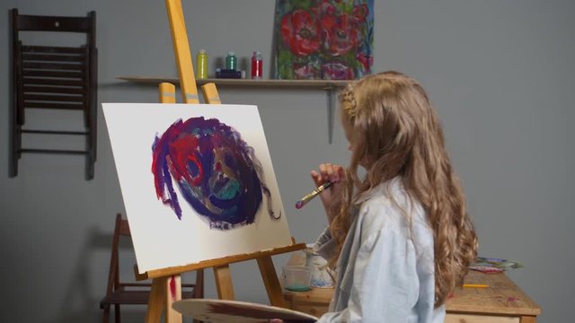 Girl draws a picture and looks at it 