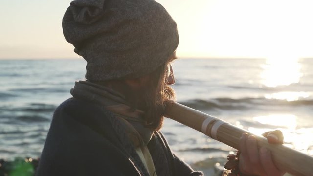 Close up man holding bansuri traditional Indian instrument playing at seashore