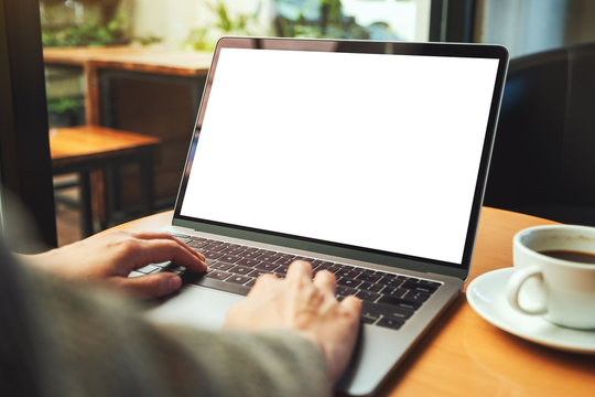 Mockup image of a woman using and typing on laptop computer with blank white desktop screen in cafe