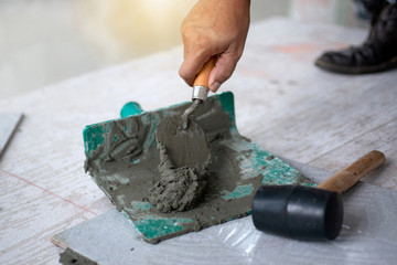 Hand of a man holding a trowel.with cement or mortar, cement mix with the trowel at the side work, Construction side work