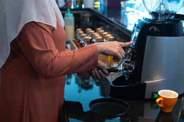 Close up Muslim female barista hand prepare the ground coffee portion for professional espresso machine, muslim concept