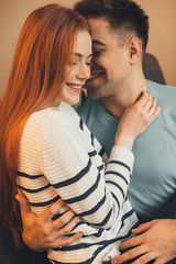 Lovely caucasian girl with red hair and freckles is embracing her lover during a sunny morning