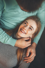 Red haired caucasian lady with freckles is lying on her boyfriend's knees and looking happily into...