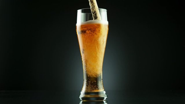 Super slow motion of pouring beer drink into glass, placed on black background. Filmed on high speed cinema camera, 1000 fps.