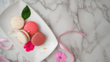Top view of Colourful Pastel Macarons on white ceramic plate  on marble desk