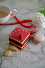 Cropped shot of raspberry cake and macarons on marble desk