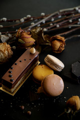 Cropped shot of chocolate cake and macarons on black table