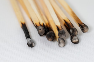 some burned matches lie side by side on a white base