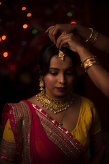 Portrait of an Indian Bengali beautiful brunette woman in front of the colorful light bokeh background created by tiny chain lights  in the evening of Diwali. Indian lifestyle and religion.