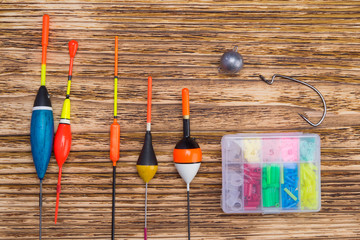 set of multi-colored floats for fishing, sinker and hook, on a dark wooden background