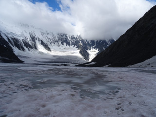 Fototapeta premium view of the mountains from the glacier to the slopes and peaks among the clouds against the blue sky