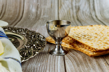 Matza, tallit and kosher kiddush on wooden background.