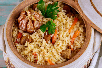 Rice with beef and vegetables in a clay pot. Close up. Asian cuisine.