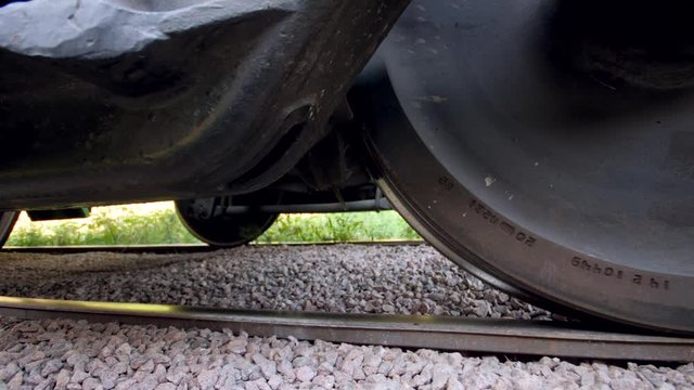 Closeup 4k dolly video of industrial railroad and big metal wheels on cargo train car. Concept of transportation and cargo using railways