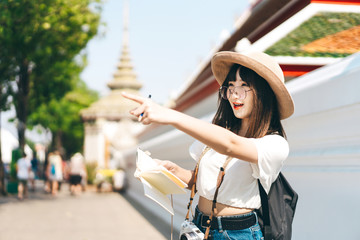 Young asian happy glasses girl traveller pointing to landmark.