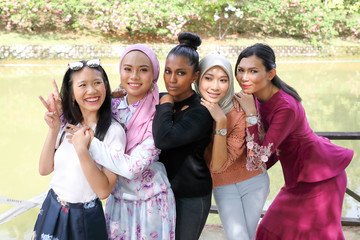 group of five woman Malay Chinese Indian Asian Malaysian outdoor green park lake nature stand talk mingle hand on friends shoulder