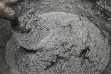 close up on fresh wet mixed cement mortar with trowel inside bucket