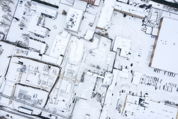 aerial view from drone of industrial area with warehouses, factory buildings and parked cars in winter