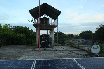 Solar panels on the roof of a tropical city house early in the morning at dawn.