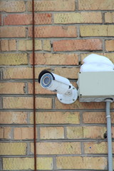 Surveillance camera mounted on brick wall of house