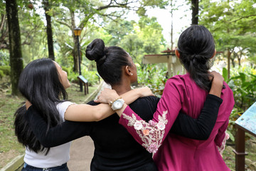 Three woman Malay Chinese Indian Asian outdoor green park walk talk mingle happy joy from behind look up