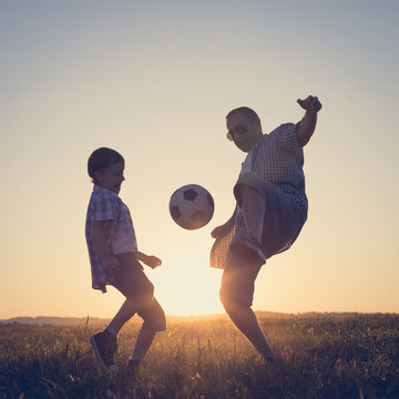 Father and young little boy playing in the field  with soccer ball.