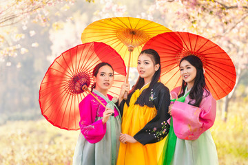 Three Korean girl wearing a hanbok wearing a yellow umbrella. Beautiful Female wearing traditional...
