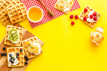 Breakfast with freashly baked belgian waffles on yellow background top-down frame copy space