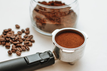 coffee horn with natural ground coffee and ground coffee in a glass jar on a white background
