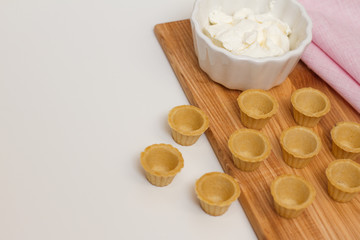 Fototapeta na wymiar Tartlets with custard or cottage cheese. Empty tartlets or pie on a white table. Food lay flat. The view from the top. The concept of preparing food for the holiday table.