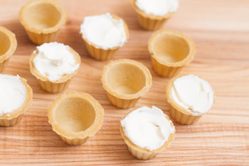 Fototapeta na wymiar Tartlets with custard or cottage cheese. Empty tartlets or pie on a white table. Food lay flat. The view from the top. The concept of preparing food for the holiday table.