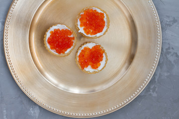 three tartlets with cream cheese and red caviar on a white background. the concept of a delicious Breakfast, buffet and snack. seafood dish. the view from the top. space for text.