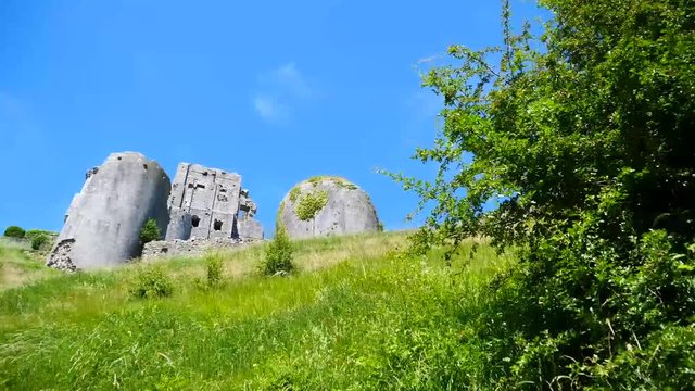 Looking up at and passing a tall, old castle on the road