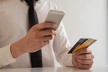 The hands of business people holding credit cards and smartphones for online shopping and paying via the internet