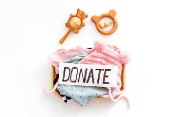 Donate text. Box with clothes for kids on white background top-down