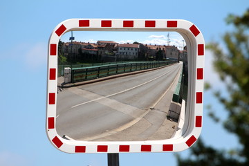 New convex rectangular traffic mirror with red and white striped frame mounted on strong metal pole...