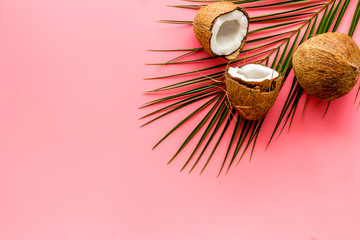 Fototapeta na wymiar Exotic background with coconuts and palm leaves on pink background top-down frame copy space