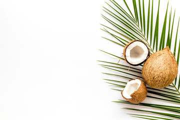 Exotic background with coconuts and palm leaves on white background top-down frame copy space