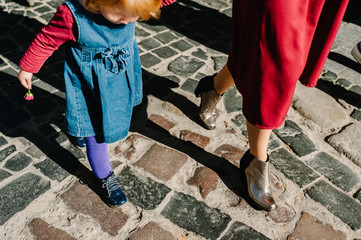 Happy family: mom hold daughter with flower enjoying time together, walk on the street city in country Europe. View in the bottom.