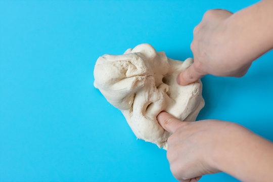 Salt dough for modeling in the hands of a child on a blue background